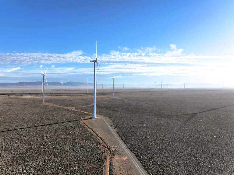 Wind turbines on desert landscape under blue sky
