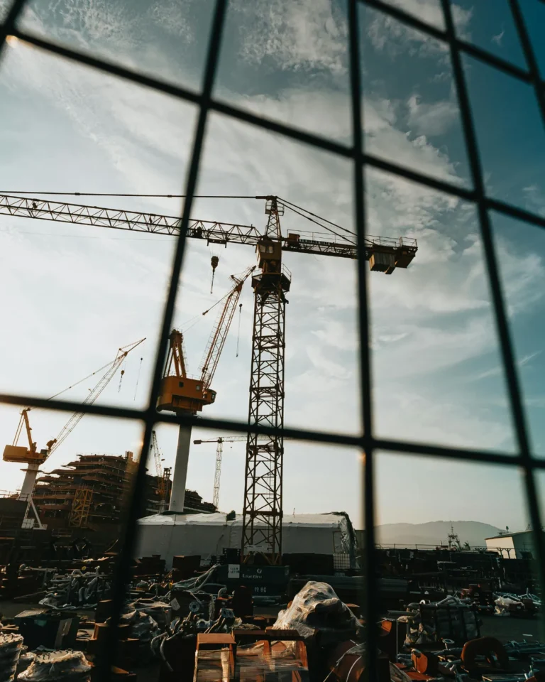 Construction cranes at industrial worksite under blue sky