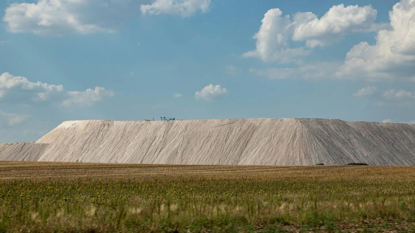 Large salt mound beside grassy field under sky